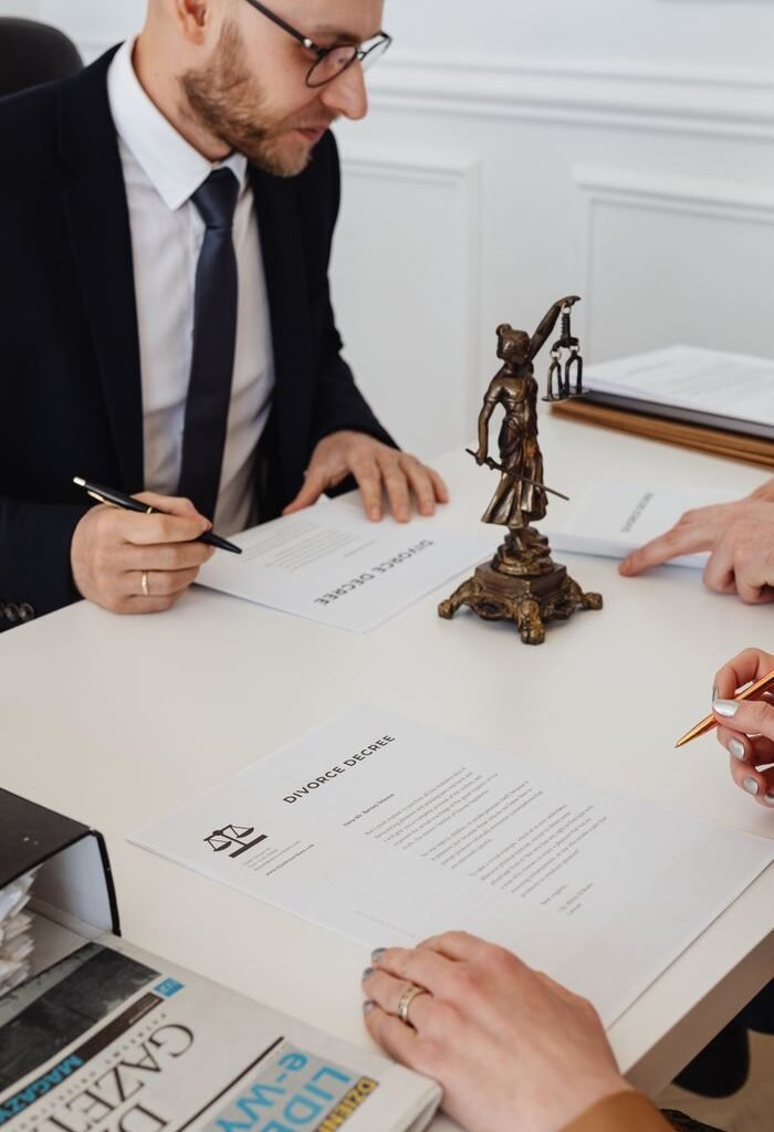 Lawyers reviewing and signing divorce decree documents in a formal office setting.
